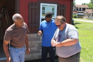 University of Illinois Extension director Jody Johnson exchanges contact information with Cairo residents Lee Wright and son Roman Wright. The agency’s office in southern Illinois is launching a vaccination education program that aims to reach this storied city on the banks of the Mississippi and Ohio rivers. (Cara Anthony/KHN)