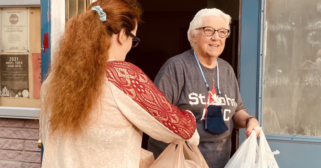 donna williams hands woman a bag of food outside of dinner church