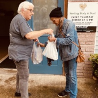 woman hands another a meal