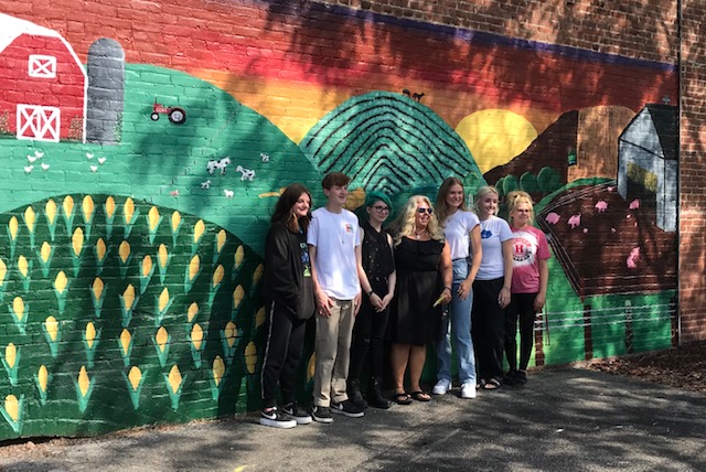 students posing in front of agriculture mural