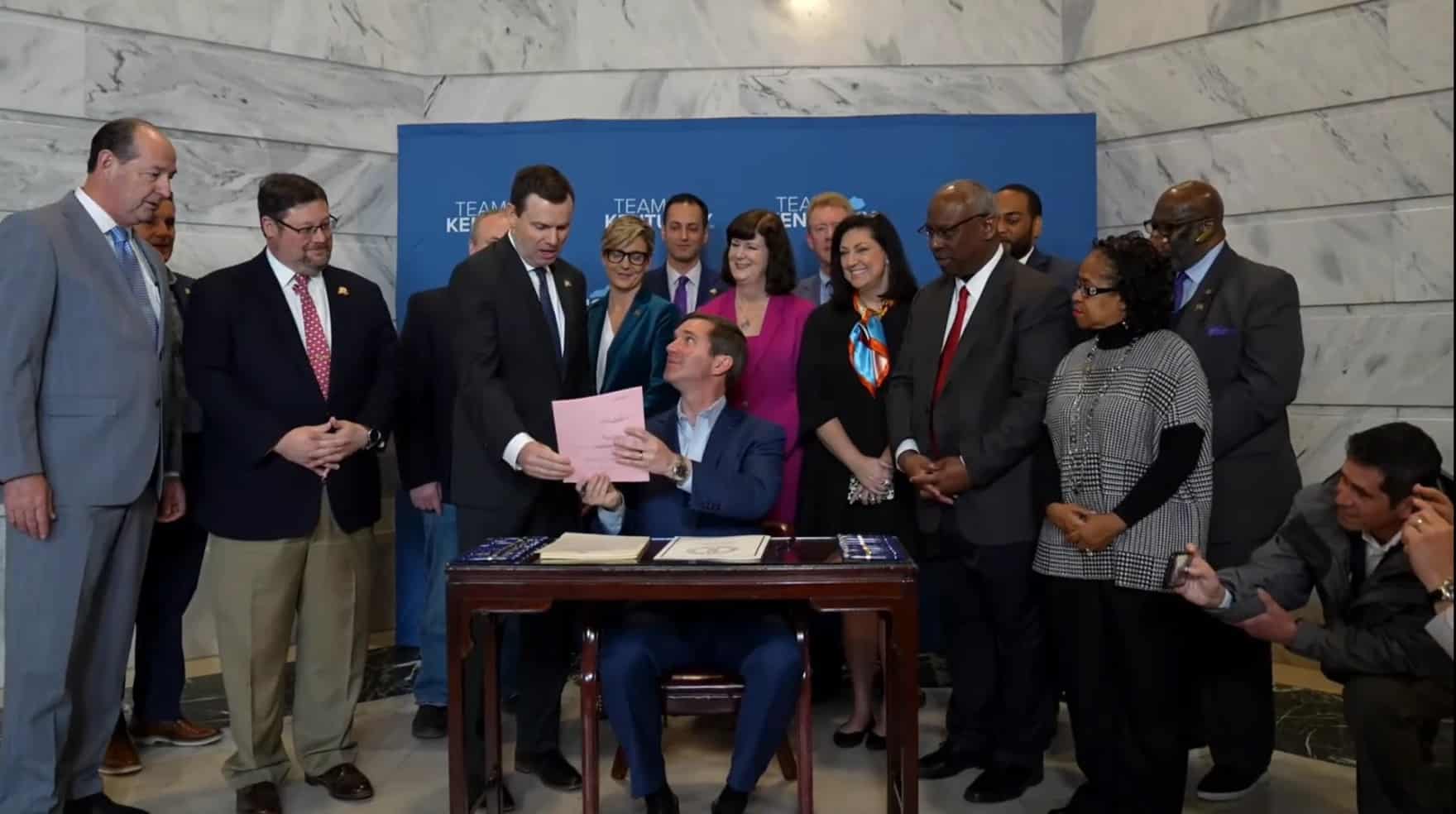 Democratic Gov. Andy Beshear hands a copy of the new medical cannabis law to Republican Sen. Steve West, the bill's primary sponsor. (Screenshot)