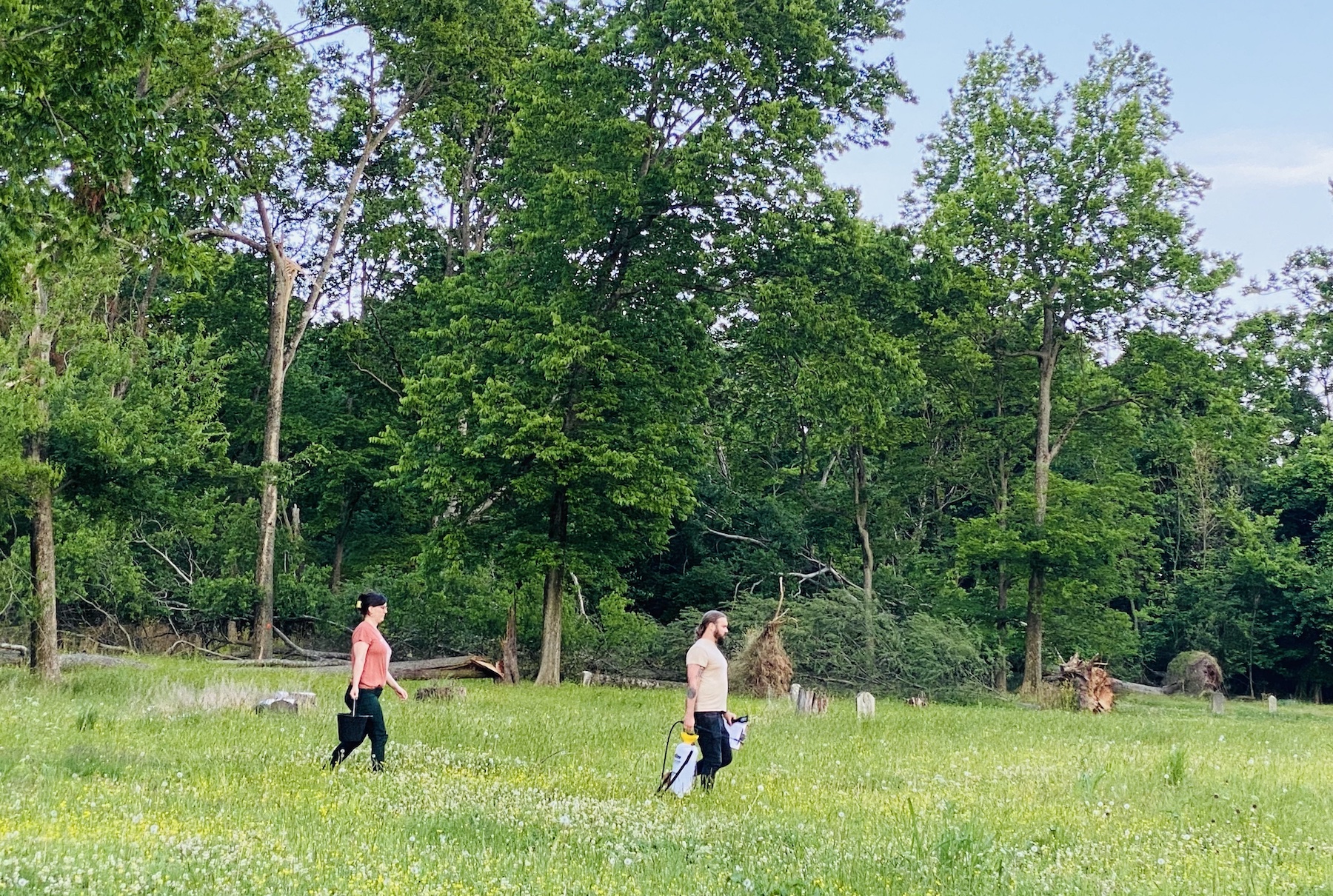 Volunteers Matt Freeman (right) and Pyper West carry water and cleaning supplies Tuesday, May 30, 2023, across the Union Benevolent Society Cemetery. (Hoptown Chronicle photo by Jennifer P. Brown)