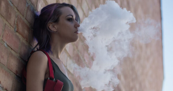 girl vaping against wall
