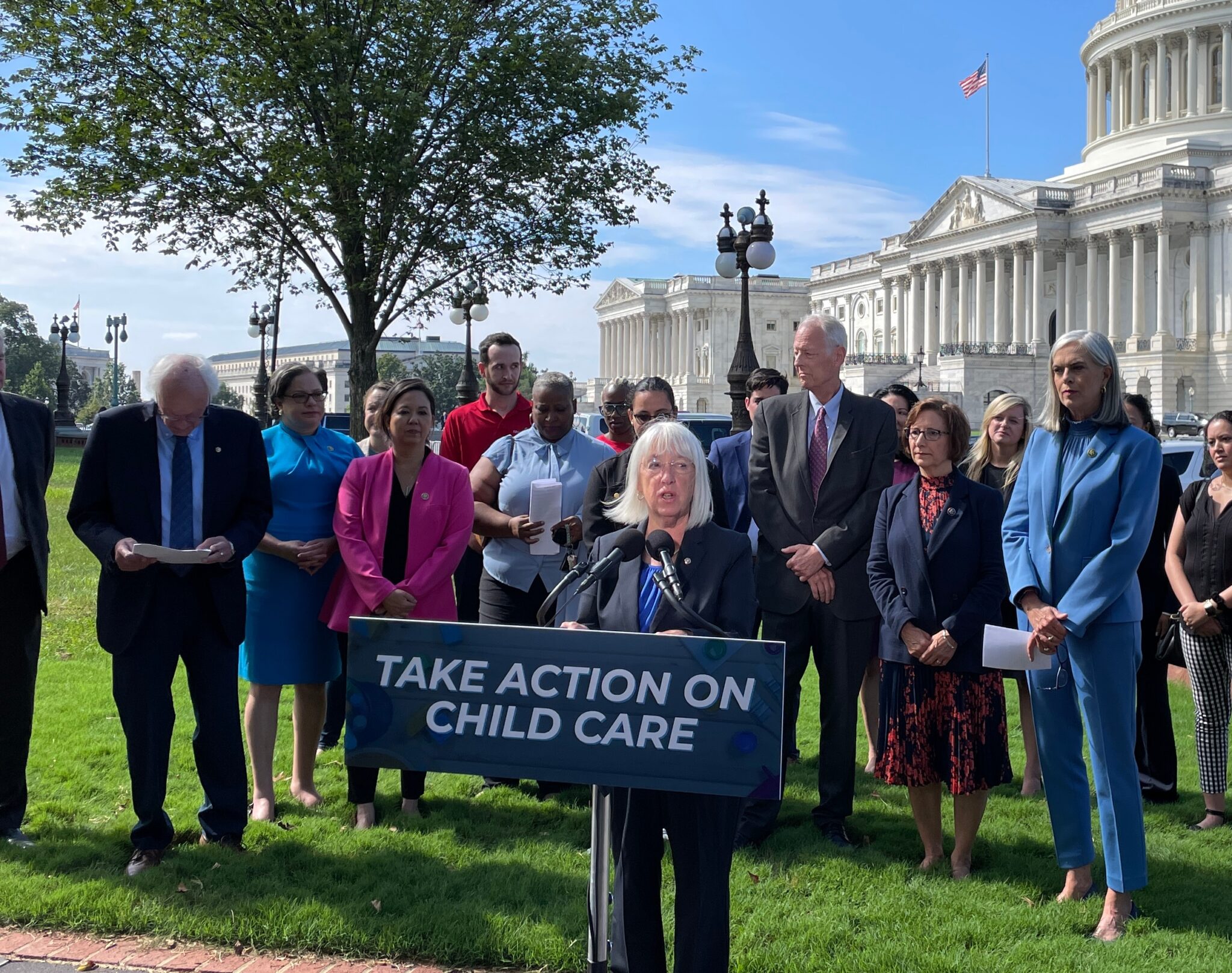 senator speaking of capitol lawn with child care sign