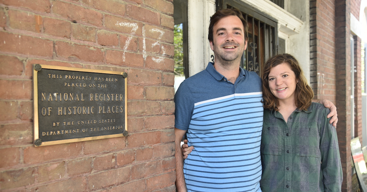 Grace and Brendan Abernethy in front of historic marker on building
