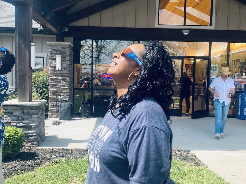 woman with eclipse viewing glasses looks to sky