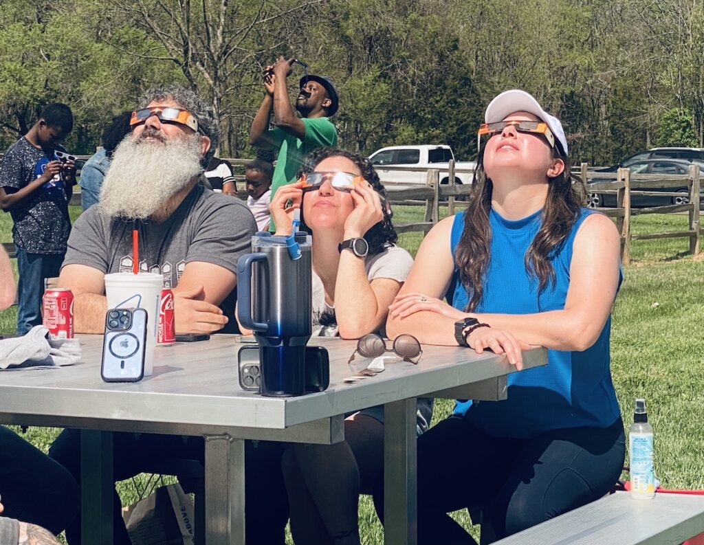 people at table watching eclipse