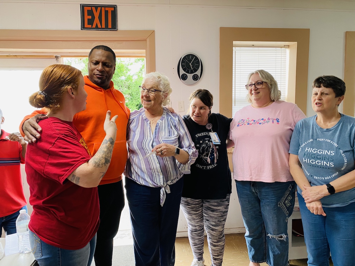 Retired NBA player Chris Whitney huddles up with dinner church volunteers (from left) Abby Hess. Donna Williams, Crystal Carn, Paige Bates and Amy Montgomery on Thursday, May 2, 2024, at Aaron McNeil House. (Hoptown Chronicle photo by Jennifer P. Brown)