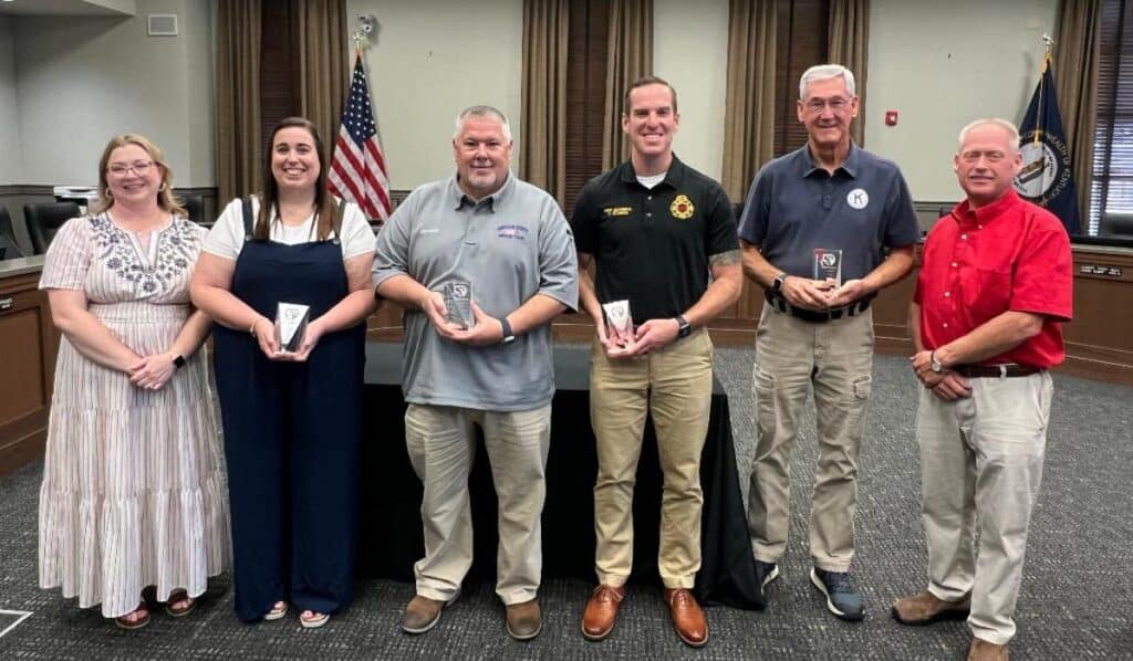 Mayor's Community Awards post with trophies alongside mayor