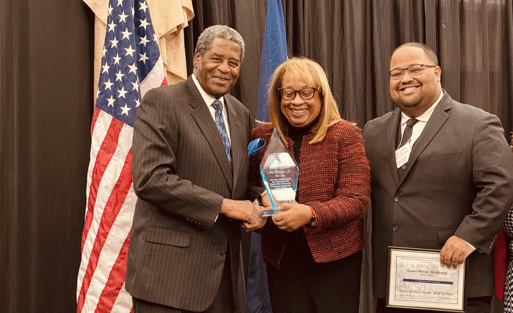 Hopkinsville native and Kentucky Human Rights Commission chairman Dr. Raymond Burse (left) presents a trophy to Linda McHenry during her late father's induction into the Kentucky Civil Rights Hall of Fame on Friday, Nov. 22, at the James E. Bruce Convention Center. The honoree's grandson, Louis P. McHenry III, helped accept the trophy and a certificate. (Hoptown Chronicle photo by Jennifer P. Brown)