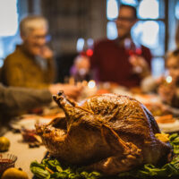 Thanksgiving stuffed turkey on dining table with family in the background