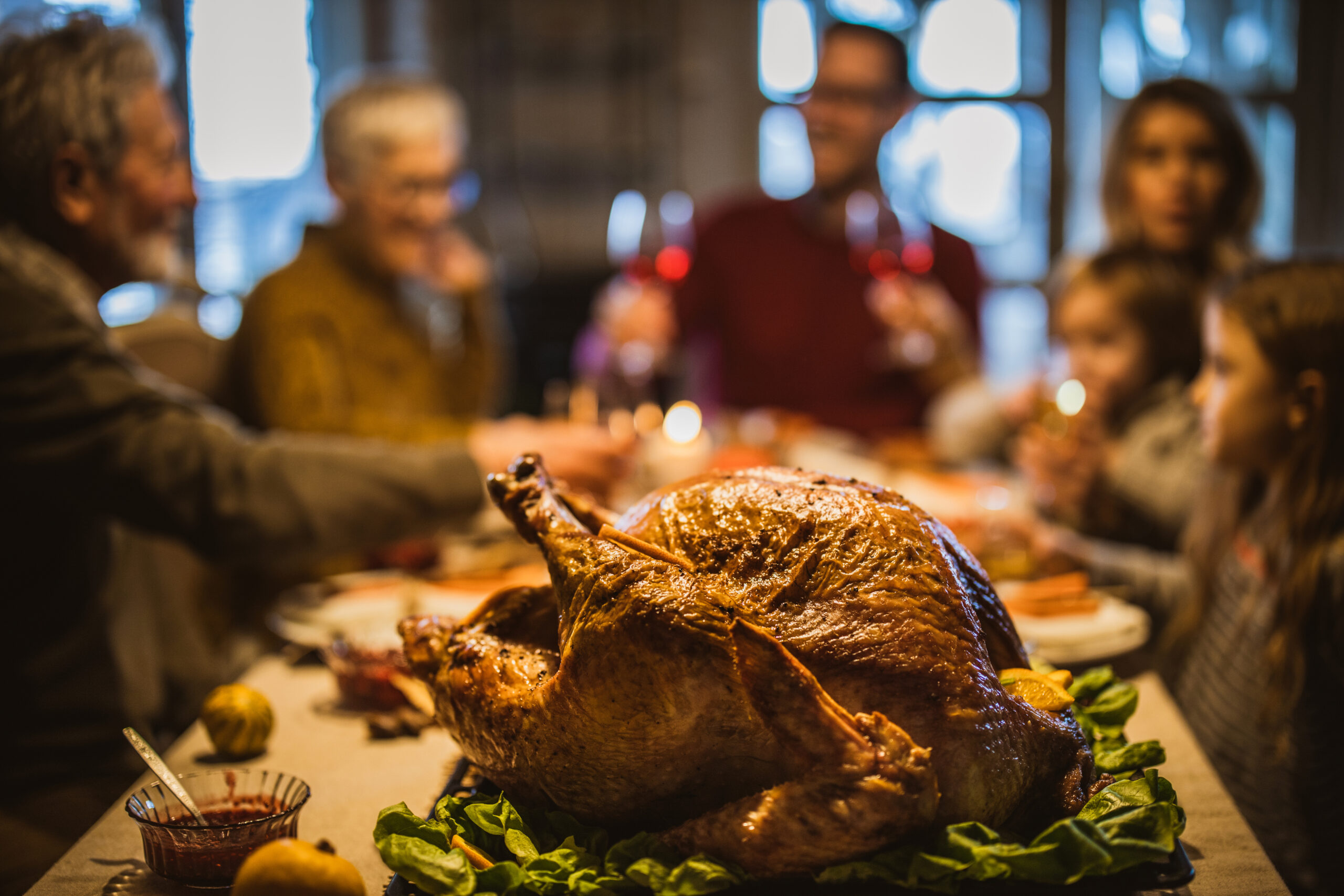 Thanksgiving stuffed turkey on dining table with family in the background