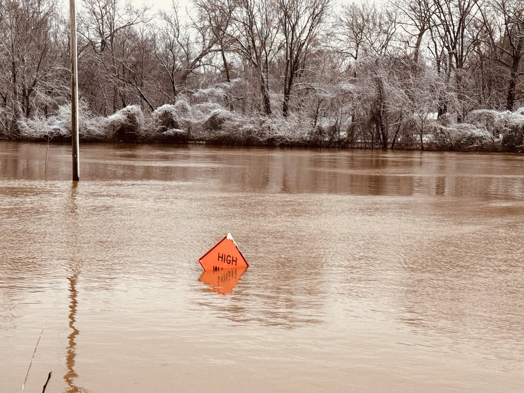 Little River overflowed its banks and by Sunday morning, Feb. 16, 2025, had nearly covered a "high water" warning sign in the middle of Old Clarksville Park next to Walgreens. (Hoptown Chronicle photo by Jennifer P. Brown)