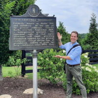 man next to historical marker