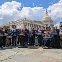 group of veterans and lawmakers holding signs