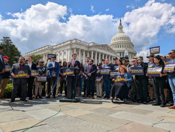 group of veterans and lawmakers holding signs