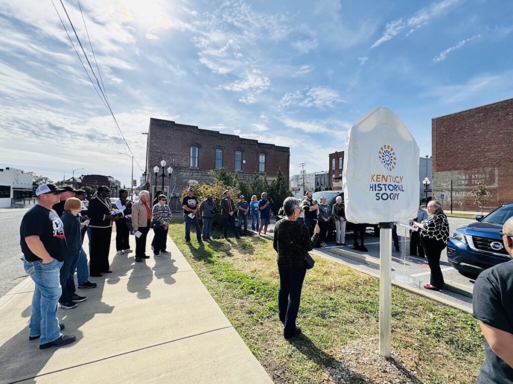 large group in front of covered historical marker