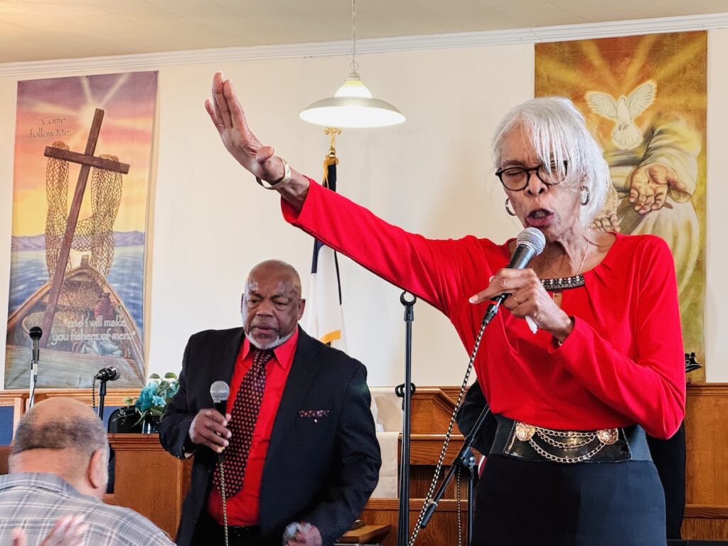woman singing gospel wth man behind her