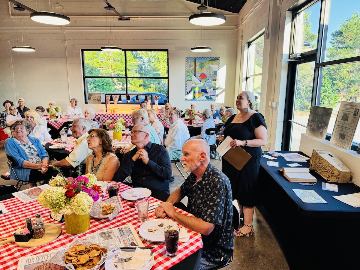 Alissa Keller (standing at right), executive director of the Museums of Historic Hopkinsville-Christian County, speaks about Hotel Latham during a program Tuesday, Aug. 4, 2026, at The Crusty Pig, which stands today on the site of the hotel that was destroyed by a fire on Aug. 4, 1940. (Hoptown Chronicle photo by Jennifer P. Brown)