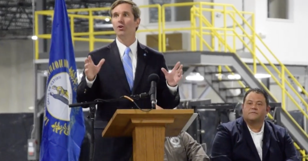 Randall Weddle, then a candidate for London mayor, listens as Gov. Andy Beshear helps celebrate the opening of WB Transport’s new warehouse in April 2022. (Screenshot with permission of WYMT)