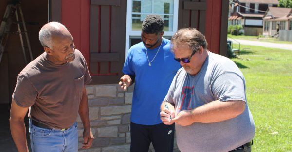 University of Illinois Extension director Jody Johnson exchanges contact information with Cairo residents Lee Wright and son Roman Wright. The agency’s office in southern Illinois is launching a vaccination education program that aims to reach this storied city on the banks of the Mississippi and Ohio rivers. (Cara Anthony/KHN)