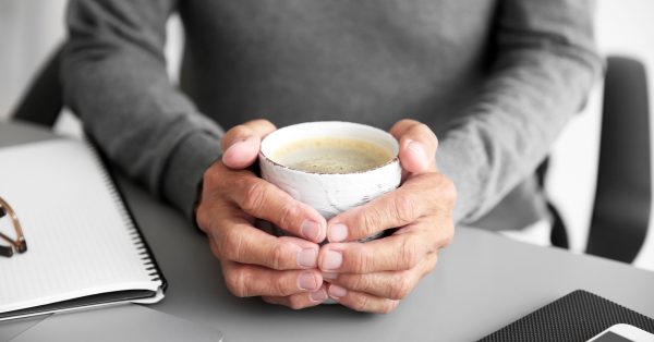 older hands holding coffee cup