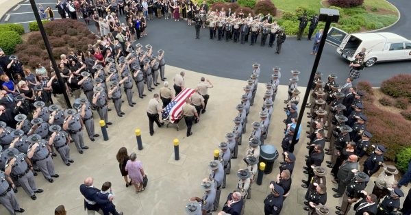 Kentucky State Police troopers salute as Jody Cash's casket is wheeled out to the hearse on Saturday, May 21, 2022. (Photo by Liam Niemeyer, WKMS)