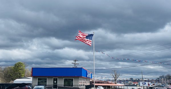 The March 3, 2023, storm whips an American flag on a car lot pole on Fort Campbell Boulevard near Walnut Street. (Hoptown Chronicle photo by Jennifer P. Brown)