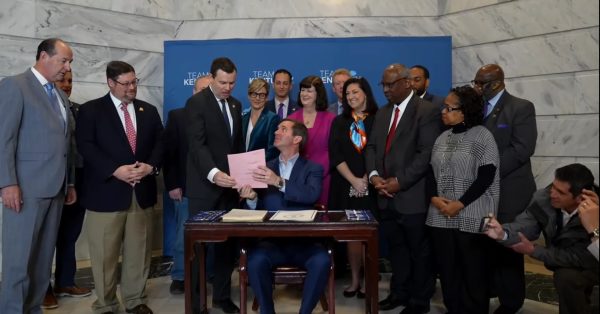 Democratic Gov. Andy Beshear hands a copy of the new medical cannabis law to Republican Sen. Steve West, the bill's primary sponsor. (Screenshot)