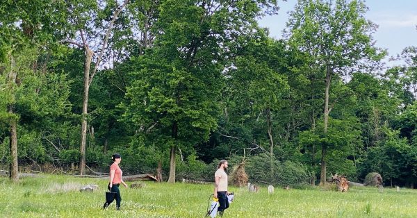Volunteers Matt Freeman (right) and Pyper West carry water and cleaning supplies Tuesday, May 30, 2023, across the Union Benevolent Society Cemetery. (Hoptown Chronicle photo by Jennifer P. Brown)