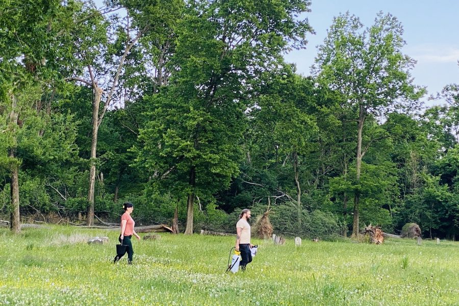 Volunteers Matt Freeman (right) and Pyper West carry water and cleaning supplies Tuesday, May 30, 2023, across the Union Benevolent Society Cemetery. (Hoptown Chronicle photo by Jennifer P. Brown)