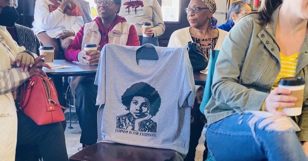A bell hooks T-shirt is draped across a chair among several people gathered Feb. 11, 2023, at The Corner Coffeehouse for a conversation about the writer's work. (Hoptown Chronicle photo by Jennifer P. Brown)
