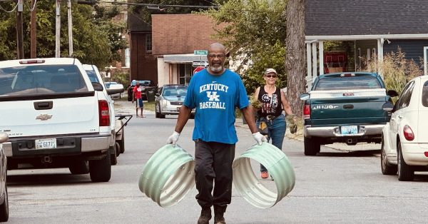 Durrett Avenue Neighborhood Association president Ardell Owens carries frames for small plant beds on Saturday, June 22, 2024, as he walks up Bryan Street. City Councilwoman Jamie Lienberger follows Owens with plants. (Hoptown Chronicle photo by Jennifer P. Brown)