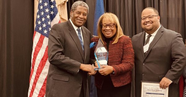 Hopkinsville native and Kentucky Human Rights Commission chairman Dr. Raymond Burse (left) presents a trophy to Linda McHenry during her late father's induction into the Kentucky Civil Rights Hall of Fame on Friday, Nov. 22, at the James E. Bruce Convention Center. The honoree's grandson, Louis P. McHenry III, helped accept the trophy and a certificate. (Hoptown Chronicle photo by Jennifer P. Brown)