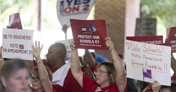 Signs hoisted Aug. 3, 2024, by members of the Fancy Farm audience express conflicting views on the school funding amendment that Kentucky voters will decide in November. (Kentucky Lantern photo by Austin Anthony)