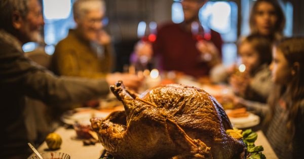 Thanksgiving stuffed turkey on dining table with family in the background